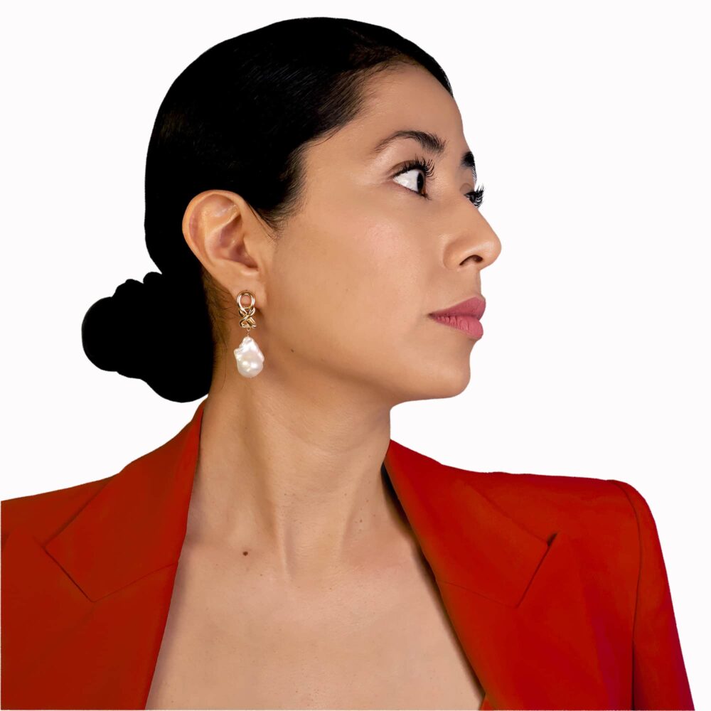 Primer plano de perfil de una modelo que luce un pendiente Origen chapado en oro con una perla barroca, perteneciente a la colección Musubi.